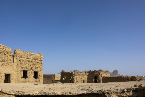 Ruins of an abandoned mudbrick village with mountain peaks visible on the horizon, Ad Dakhiliyah Region, Al Hamra, Oman