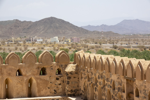 View from atop the crenellated ramparts of Nizwa Fort overlooking palm groves and mountains, Ad Dakhiliyah Region, Nizwa, Oman