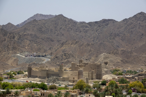 Panoramic view of Bahla Fort's mudbrick walls and towers backed by rugged mountains, Ad Dakhiliyah Governorate, Bahla, Oman