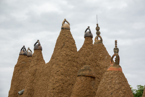 A row of ceramic-capped pinnacles rises against green foliage at the 17th-century Sudano-Sahelian mosque, Savanes district, Kouto, Ivory Coast