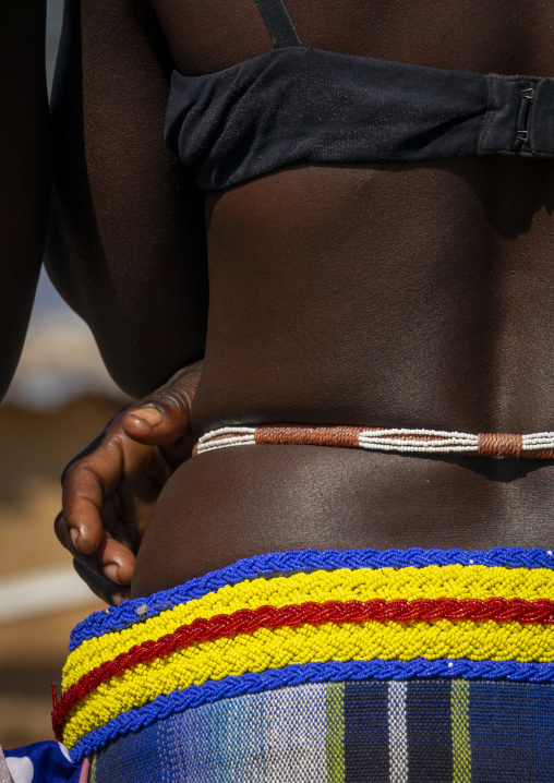Close-up of a woman's lower back with a beaded belt above a striped waistband and plaid skirt, Cunene Province, Cahama, Angola