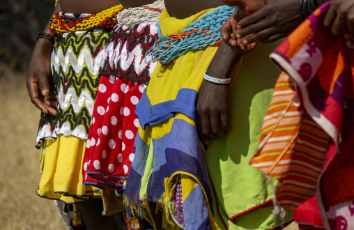 Close-up of several women's colorful patterned skirts and beaded waistbands standing side by side, Cunene Province, Cahama, Angola