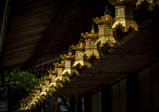 Rows of golden lanterns hanging under a temple eave, Wakayama pr