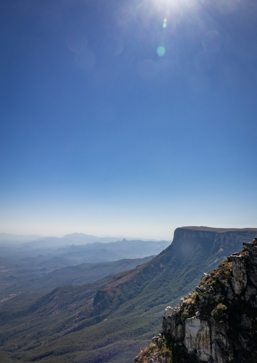 Panoramic view over the layered mountains and cliff edge of the Serra da Chela escarpment with sun flare in the sky, Huila Province, Humpata, Angola