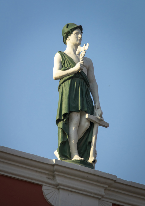 Close-up of a painted statue of Mercury wearing a winged helmet and holding a caduceus against a clear sky, Luanda Province, Luanda, Angola
