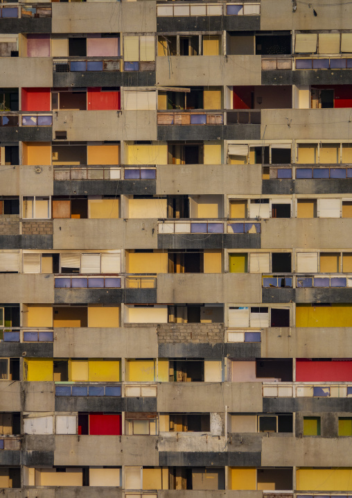 Rows of weathered concrete balconies with multicolored doors cover the facade of an abandoned apartment building, Luanda Province, Luanda, Angola
